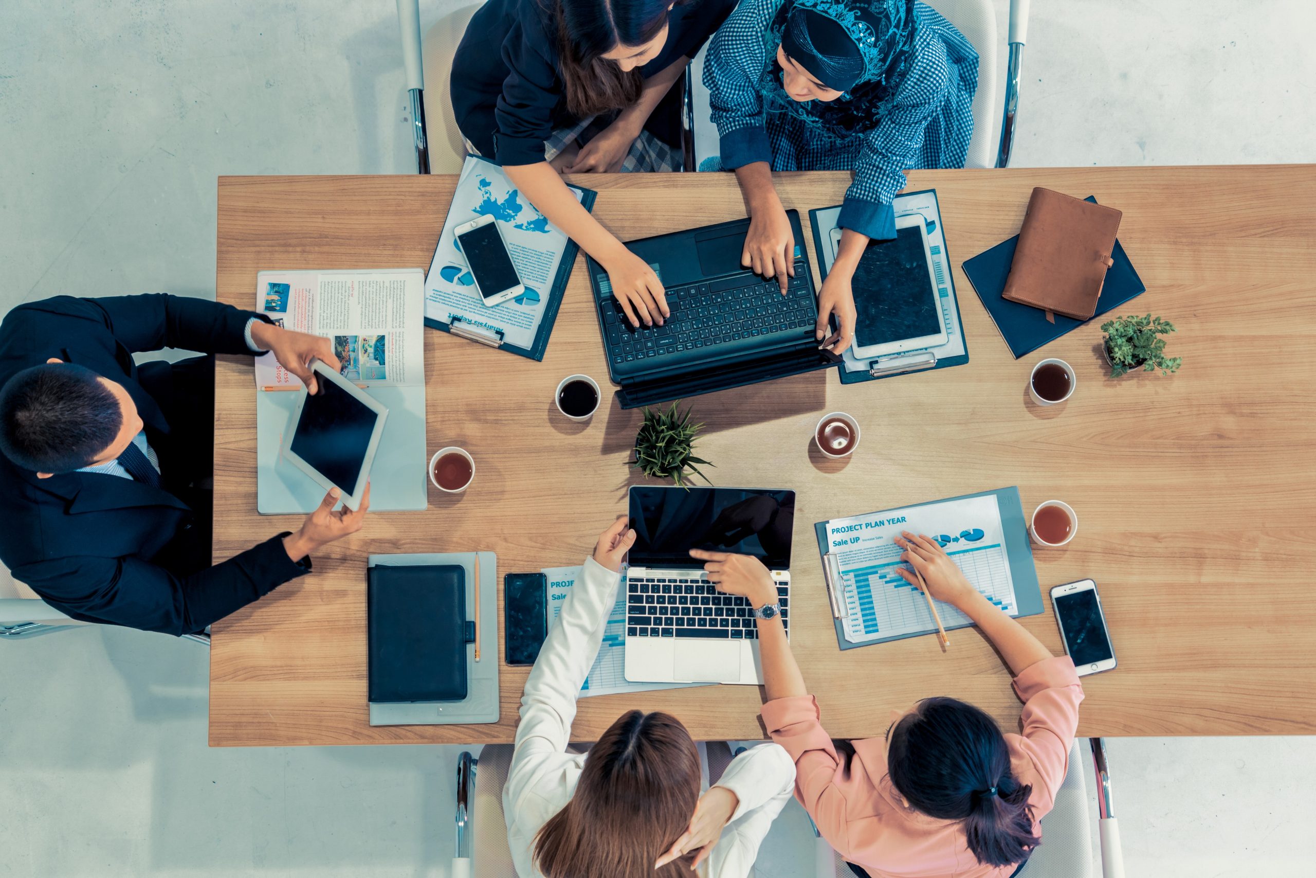 Vue de dessus de l'homme d'affaires exécutif dans la réunion de groupe avec d'autres hommes d'affaires et femmes d'affaires dans le bureau moderne avec ordinateur portable, café et documents